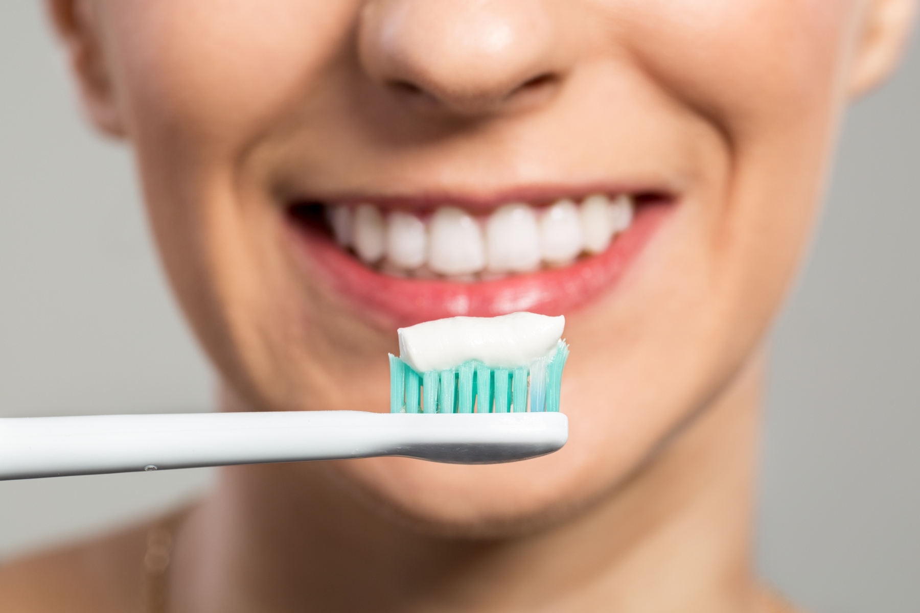 Smiling woman holding a toothbrush with toothpaste for daily dental care